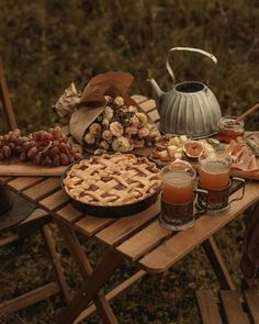 an outdoor picnic table with pies, fruit and other food items on the table