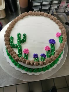 a cake decorated with flowers and cactus on a table