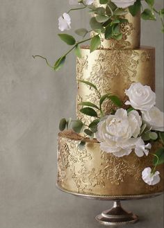 a gold wedding cake with white flowers on top