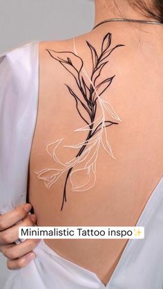 the back of a woman's shoulder with flowers on it and leaves drawn in white ink