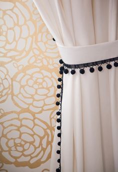 a curtain with black beads hanging from it's side next to a wallpaper