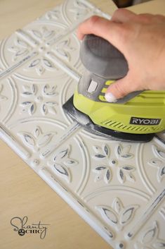 a person is using a sander on a tile pattern that has been stenciled