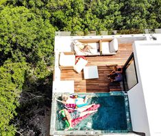 an aerial view of two people laying on the ground in a pool surrounded by trees