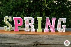 the word spring spelled with polka dots in pink, green and white letters on a wooden surface