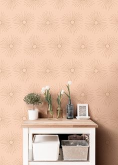 a white cabinet with some flowers on top of it next to a pink wallpaper