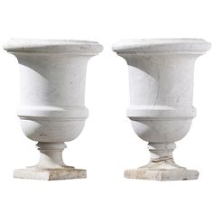 two white marble vases sitting next to each other