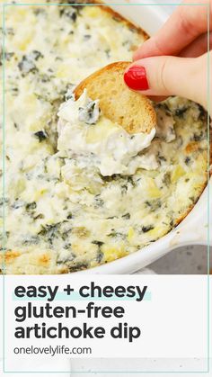 a hand dipping a piece of bread into a bowl of spinach artichoke dip