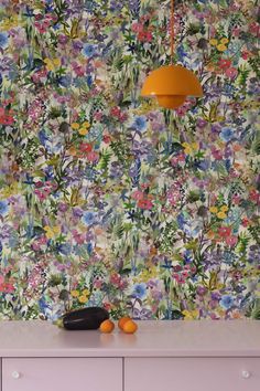 the wallpaper in this kitchen is colorful and has many flowers on it, as well as an orange lamp