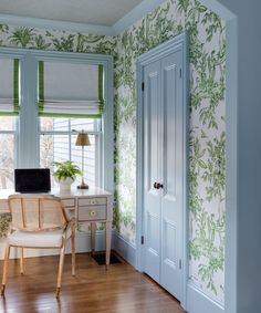 a desk and chair in a room with green wallpaper on the walls next to a window