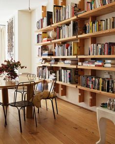 a dining room table surrounded by bookshelves and chairs