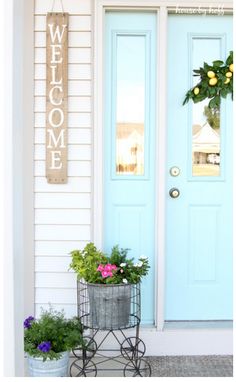 a welcome sign on the front door of a house with potted plants and flowers