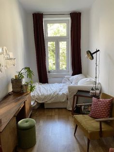 a small bedroom with a bed, desk and chair in the corner next to a window