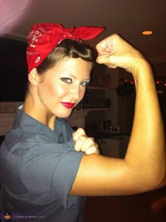 a woman is flexing her muscles with a red bow on her head and arms