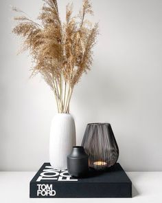 two vases sitting on top of a book next to each other with plants in them