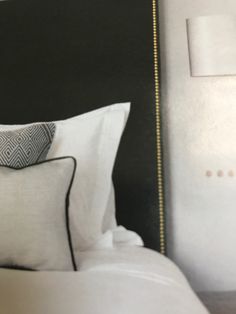 a black headboard with white pillows and gold trimmings in a hotel room