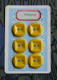 four yellow plastic buttons sitting on top of a blue and white card with the words buttons