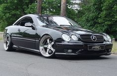 a black mercedes cls parked in front of some trees