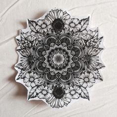 a black and white drawing of a flower on a piece of paper that is sitting on a table