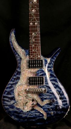 a blue and white guitar sitting on top of a black surface with an intricate design