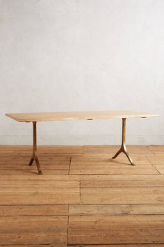 a table sitting on top of a hard wood floor next to a white wall in an empty room