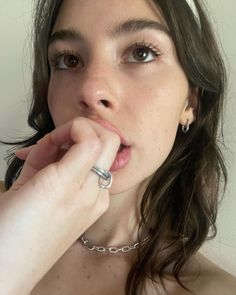 a close up of a person with a ring on her finger and wearing a necklace