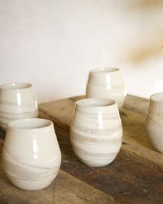 five white cups sitting on top of a wooden table