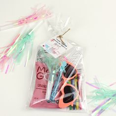 a bag filled with lots of colorful items on top of a white table next to streamers