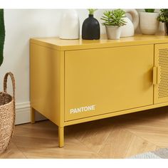 a yellow sideboard with plants on top and a basket next to it that says pantone