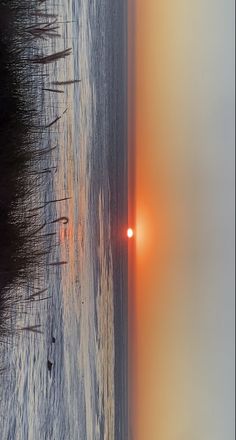 the sun is setting over the water at the beach