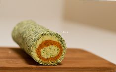 a rolled up food item sitting on top of a wooden cutting board