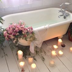 a bathtub with candles and flowers on the floor