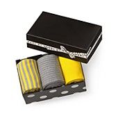 three pairs of yellow and grey striped socks in a black box with polka dot trim