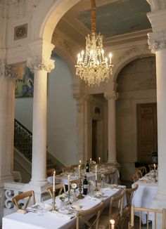 an elegant dining room with chandelier and white tablecloths set for dinner