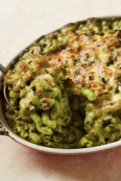 broccoli and cheese casserole in a white dish with a serving spoon