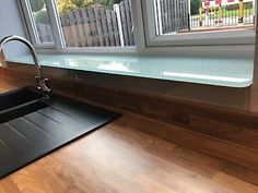 a kitchen sink sitting under a window next to a counter top with a cutting board on it