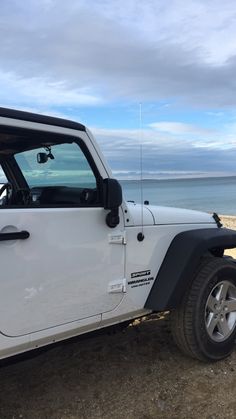 a white jeep parked on top of a sandy beach