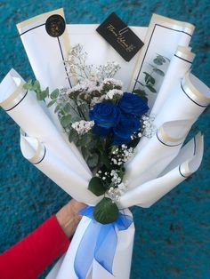 a bouquet of blue roses and baby's breath wrapped in white paper