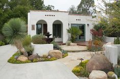 a white house surrounded by rocks and plants