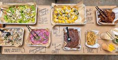 an overhead view of many different types of food on trays with utensils