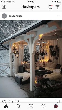 an outdoor living room with lights on the ceiling and furniture in the snow covered area