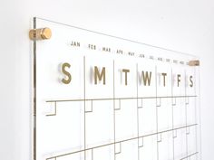 a wall mounted calendar with the words smtwiffs on it and gold accents