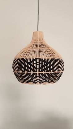 a black and white woven light fixture hanging from a ceiling lamp with an attached cord