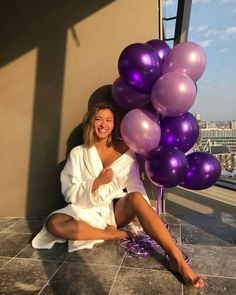 a woman sitting on the floor with purple balloons