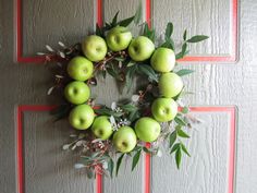 a wreath made out of green apples hanging on a wall