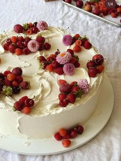 a white cake with strawberries and cherries on it