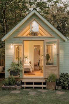 a small blue house with a porch and door leading to the bedroom area is lit up at night