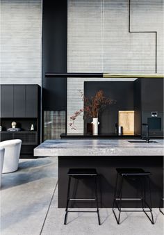 a black kitchen with two stools in front of the counter top and an island