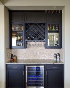 a wine cooler in the middle of a kitchen with cabinets and bottles on it's doors