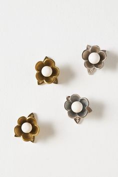 three metal flower knobs on a white surface