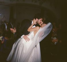 a bride and groom kissing on the dance floor in front of an audience at a wedding